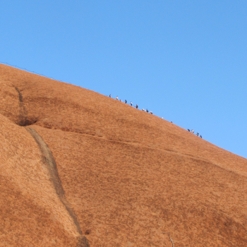 Climbers look tiny as they hike up Uluru