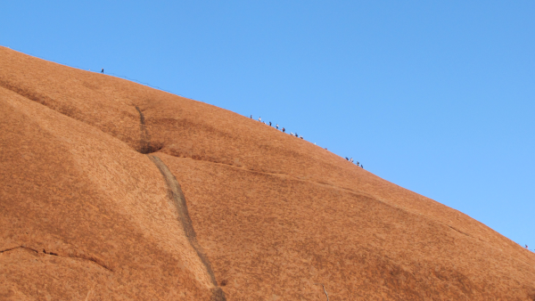 Climbers look tiny as they hike up Uluru