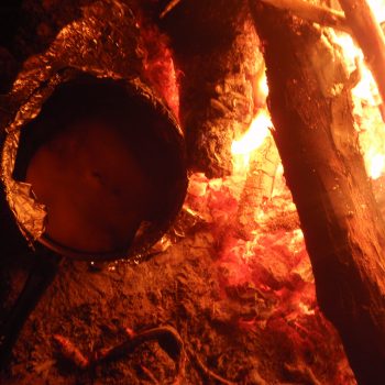 Damper bread bakes in the coals on a fire