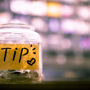 A tip jar sitting on a counter.